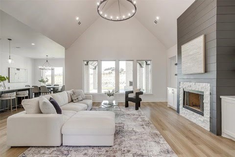 192 Top Flight Dr, Weatherford, TX 76087 - living area with high vaulted ceiling, a notable chandelier, a stone fireplace, and light wood-type flooring