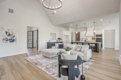 192 Top Flight Dr, Weatherford, TX 76087 - living room with high vaulted ceiling, baseboards, light wood-style flooring, and a notable chandelier