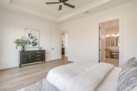 192 Top Flight Dr, Weatherford, TX 76087 - bedroom featuring ceiling fan, a raised ceiling, baseboards, light wood-type flooring, and visible vents