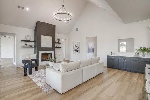 192 Top Flight Dr, Weatherford, TX 76087 - living room featuring visible vents, a fireplace, high vaulted ceiling, an inviting chandelier, and light wood-style flooring