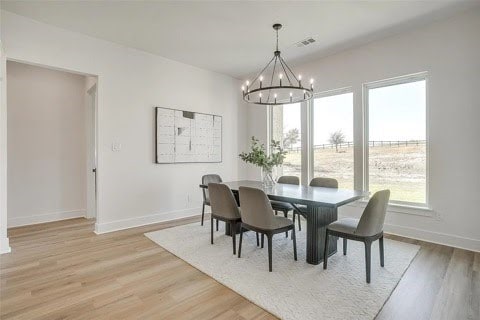 192 Top Flight Dr, Weatherford, TX 76087 - dining room featuring an inviting chandelier, baseboards, a healthy amount of sunlight, and light wood-type flooring