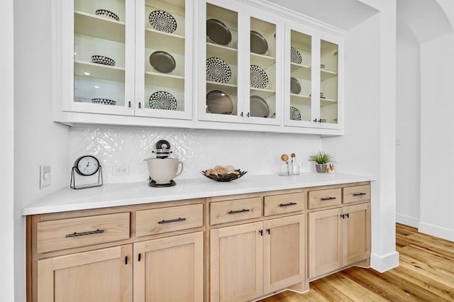 bar featuring decorative backsplash, light hardwood / wood-style flooring, and light brown cabinets