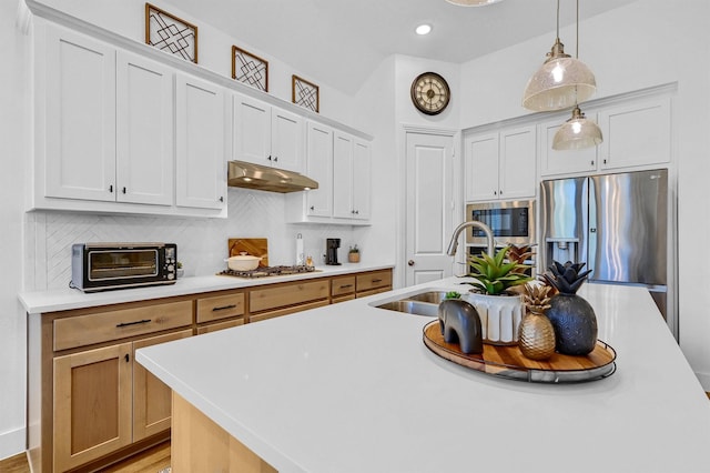 kitchen featuring a center island with sink, appliances with stainless steel finishes, decorative light fixtures, light hardwood / wood-style floors, and white cabinetry