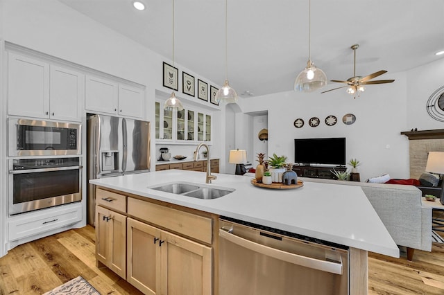 kitchen with a center island with sink, sink, light hardwood / wood-style floors, white cabinetry, and stainless steel appliances