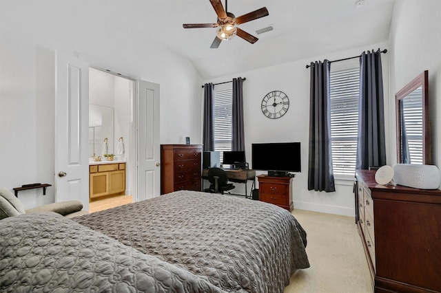 bedroom with ceiling fan, light colored carpet, lofted ceiling, and connected bathroom