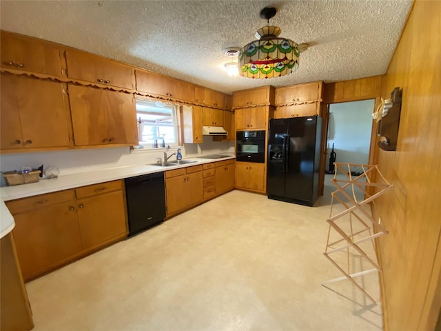 kitchen with black appliances, wood walls, sink, and a textured ceiling