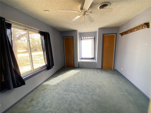 empty room featuring carpet, ceiling fan, a healthy amount of sunlight, and a textured ceiling