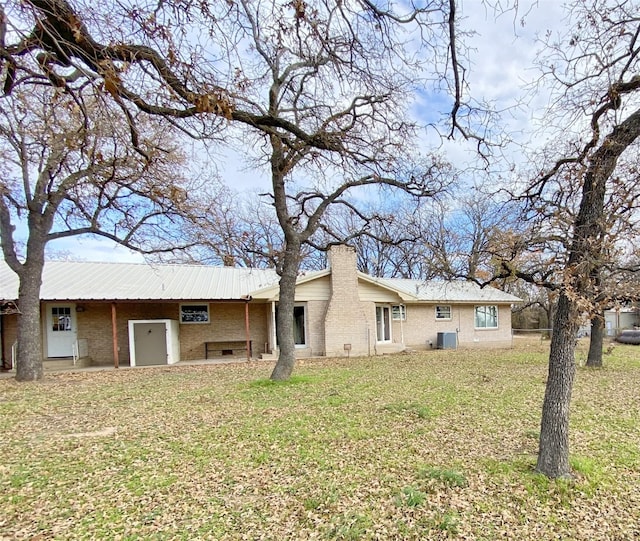 rear view of property featuring a yard and central AC