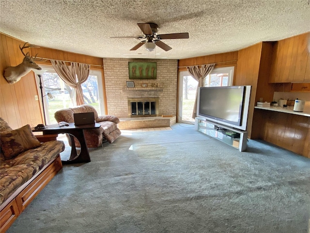 living room with carpet, a textured ceiling, wooden walls, and a healthy amount of sunlight