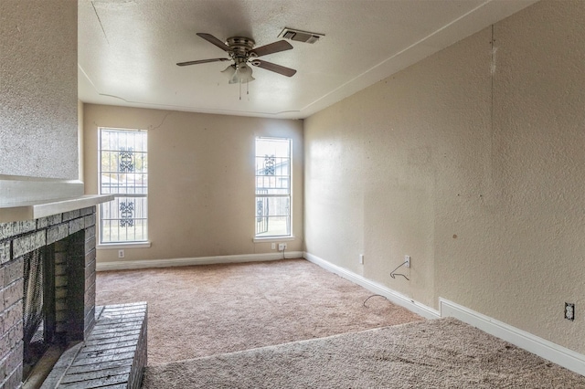 unfurnished living room featuring a fireplace, a textured ceiling, carpet flooring, and ceiling fan