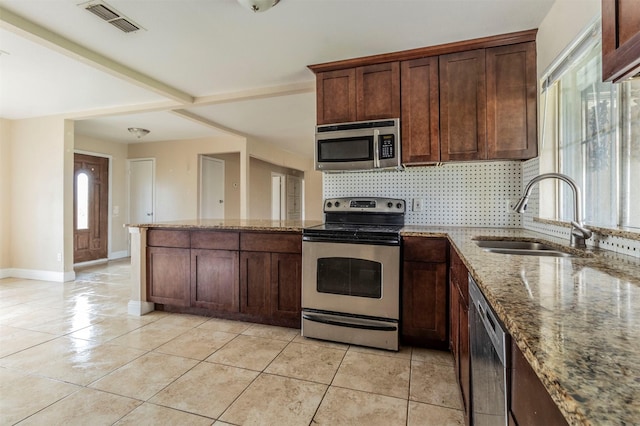 kitchen with sink, light stone counters, decorative backsplash, light tile patterned flooring, and appliances with stainless steel finishes