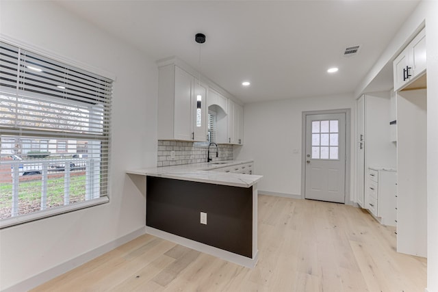 kitchen with white cabinetry, hanging light fixtures, backsplash, and kitchen peninsula