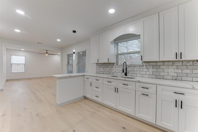 kitchen with pendant lighting, sink, decorative backsplash, and white cabinets