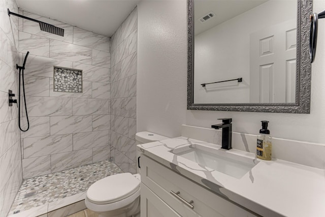 bathroom featuring vanity, tiled shower, and toilet