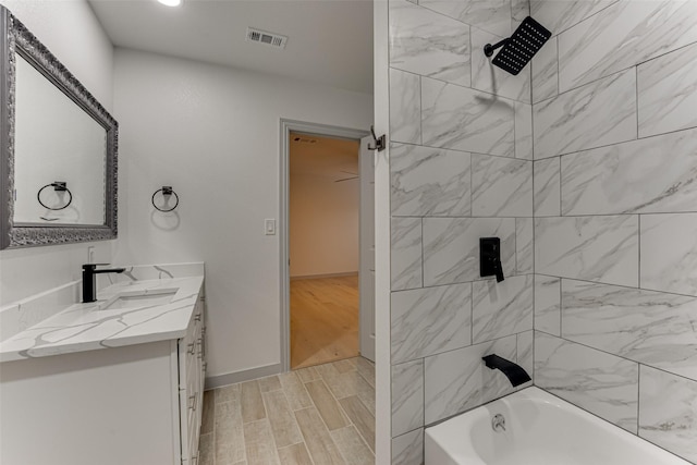 bathroom featuring tiled shower / bath and vanity