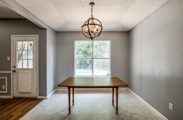 dining space featuring a notable chandelier, hardwood / wood-style floors, a textured ceiling, and a wealth of natural light