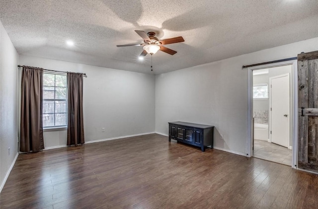 empty room with plenty of natural light, dark wood-type flooring, a textured ceiling, and ceiling fan