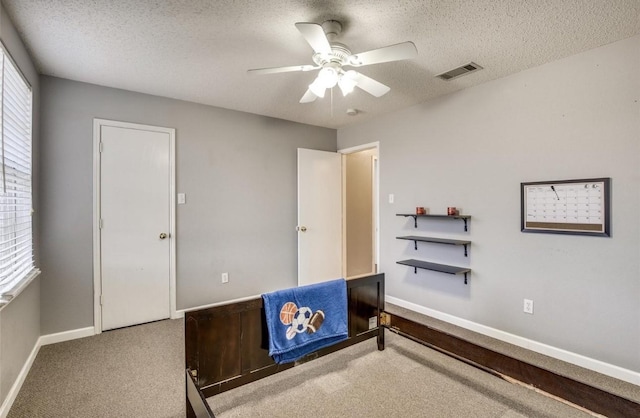 carpeted bedroom with ceiling fan and a textured ceiling