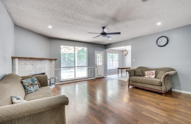 living room featuring hardwood / wood-style floors, a textured ceiling, ceiling fan, and a brick fireplace