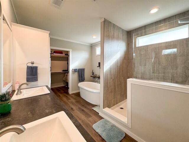 bathroom featuring separate shower and tub, vanity, wood-type flooring, and ornamental molding