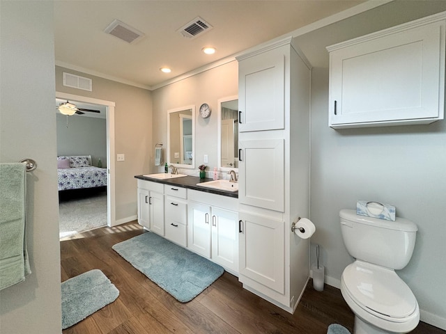 bathroom featuring vanity, crown molding, hardwood / wood-style flooring, ceiling fan, and toilet