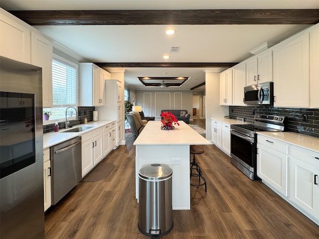 kitchen featuring sink, a breakfast bar area, appliances with stainless steel finishes, a kitchen island, and white cabinets