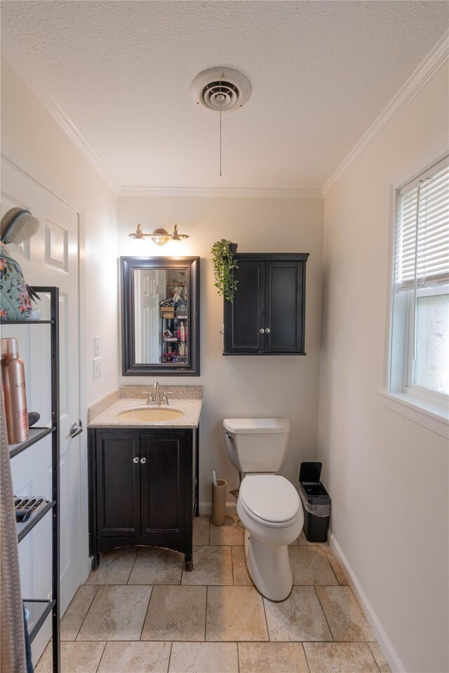 bathroom featuring vanity, toilet, ornamental molding, and a textured ceiling