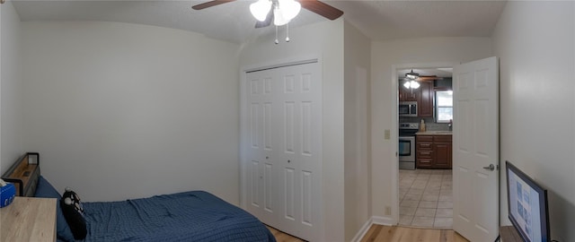 bedroom with a closet, light hardwood / wood-style flooring, ceiling fan, and sink