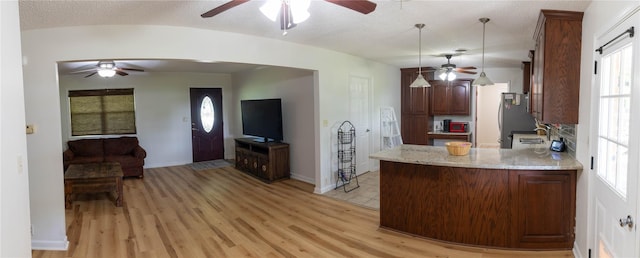 kitchen with light stone counters, sink, pendant lighting, light hardwood / wood-style floors, and lofted ceiling