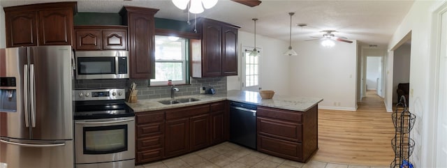 kitchen with sink, hanging light fixtures, backsplash, kitchen peninsula, and appliances with stainless steel finishes