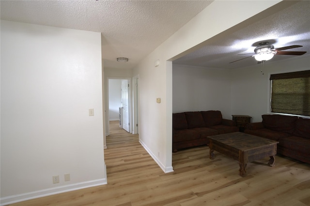 living room featuring ceiling fan, light hardwood / wood-style flooring, and a textured ceiling