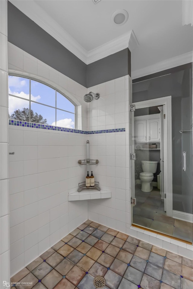 bathroom featuring a tile shower, crown molding, and toilet