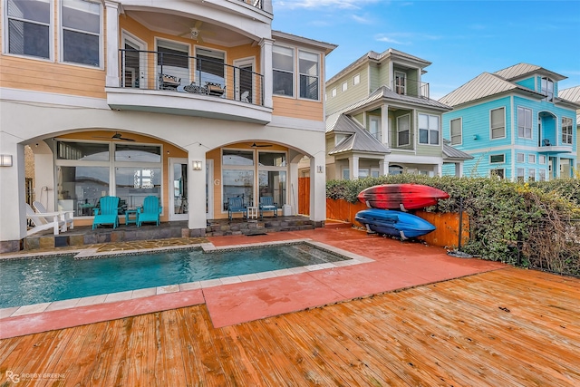 back of property featuring a pool with hot tub, ceiling fan, and a balcony