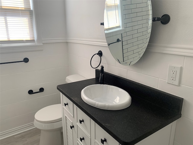 bathroom featuring hardwood / wood-style floors, toilet, vanity, and tile walls