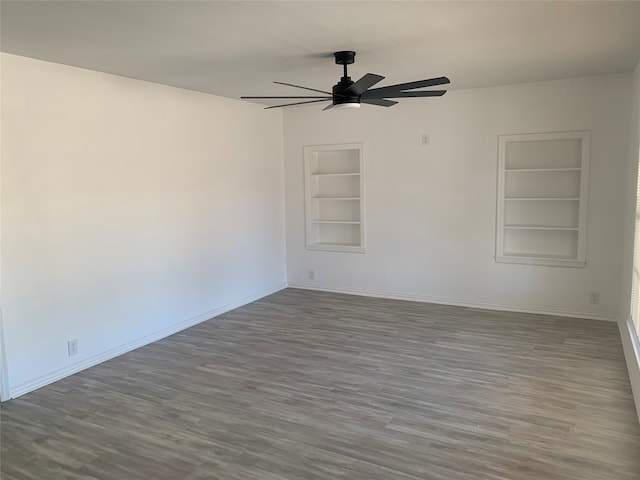 unfurnished room with ceiling fan, dark hardwood / wood-style floors, and built in features