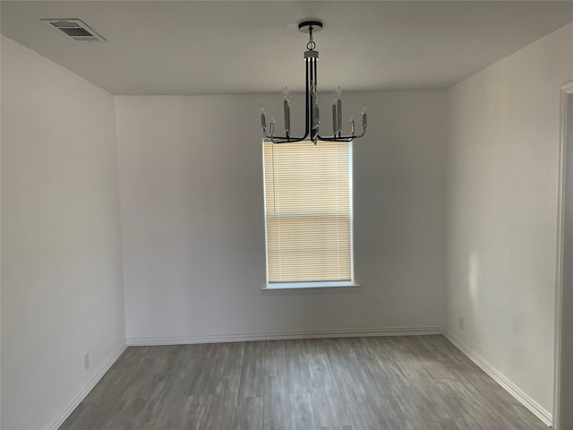 unfurnished dining area with hardwood / wood-style flooring and a notable chandelier