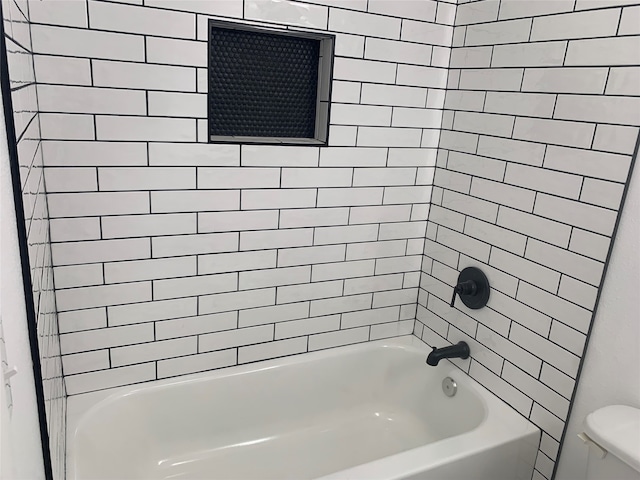 bathroom with toilet and tiled shower / bath combo