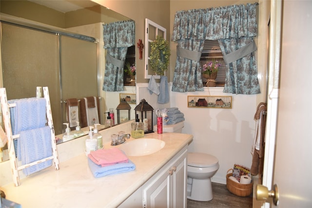 bathroom with hardwood / wood-style floors, vanity, toilet, and a shower with door