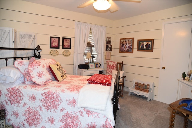 bedroom featuring carpet, ceiling fan, and wooden walls