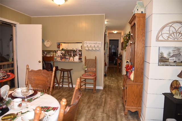 dining area featuring dark hardwood / wood-style flooring, crown molding, and wood walls