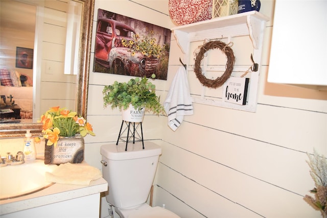 bathroom featuring vanity, toilet, and wooden walls