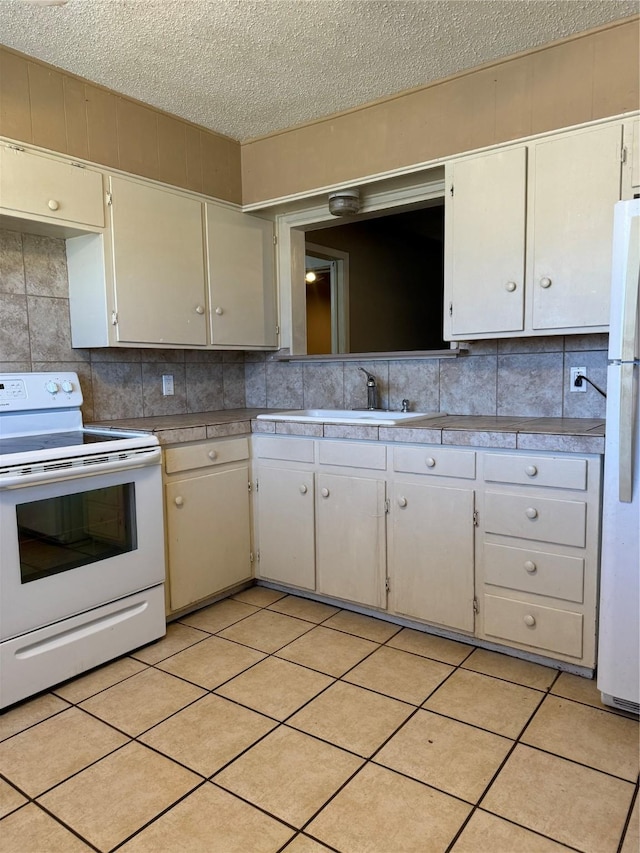 kitchen with light tile patterned flooring, sink, white appliances, and backsplash