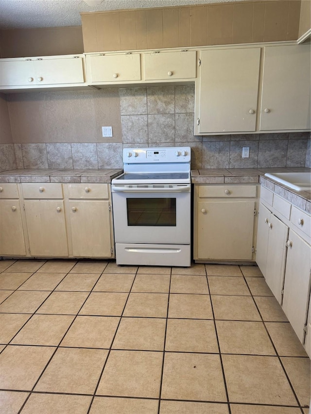 kitchen featuring white cabinets, light tile patterned floors, a textured ceiling, tasteful backsplash, and white range with electric stovetop