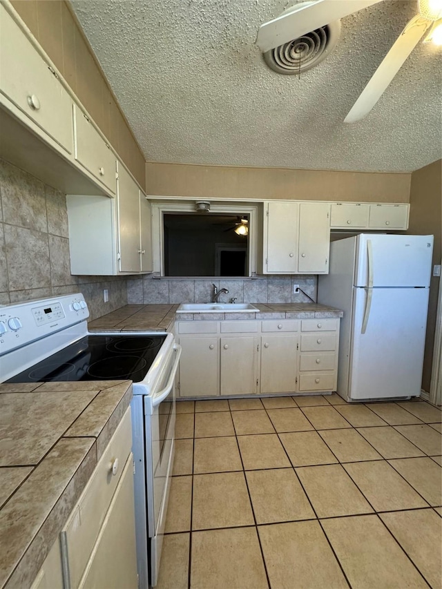 kitchen with white appliances, ceiling fan, sink, tile countertops, and light tile patterned flooring