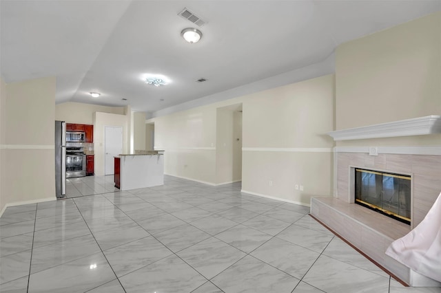 unfurnished living room with a tile fireplace and lofted ceiling