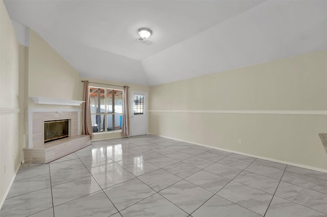 unfurnished living room with a tile fireplace, light tile patterned floors, and vaulted ceiling