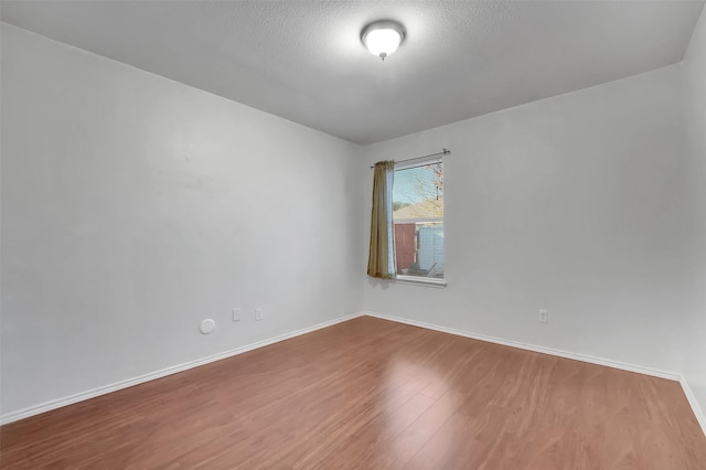 spare room with a textured ceiling and hardwood / wood-style flooring