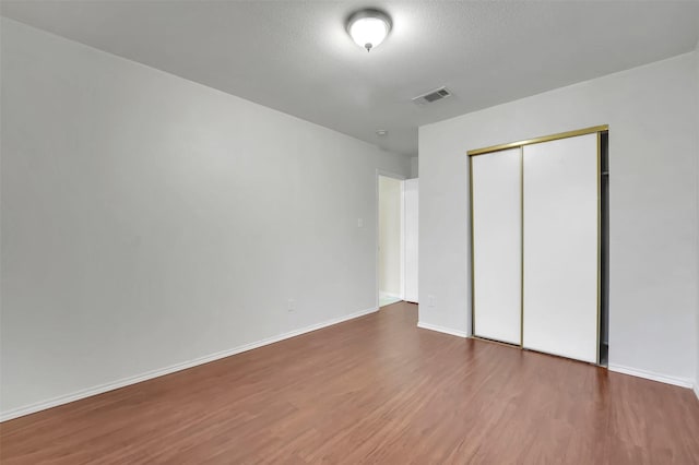 unfurnished bedroom with hardwood / wood-style floors, a textured ceiling, and a closet