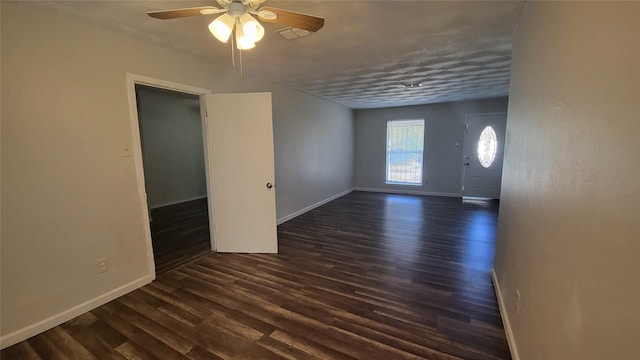 empty room with ceiling fan and dark wood-type flooring