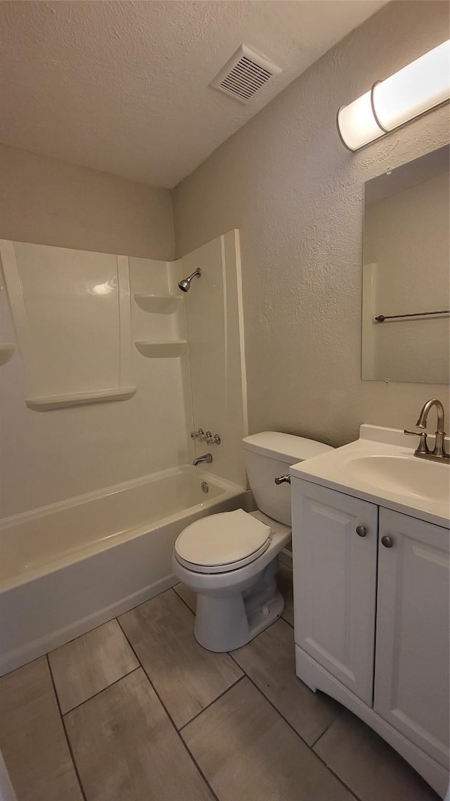 full bathroom featuring tile patterned floors, shower / bathtub combination, vanity, a textured ceiling, and toilet